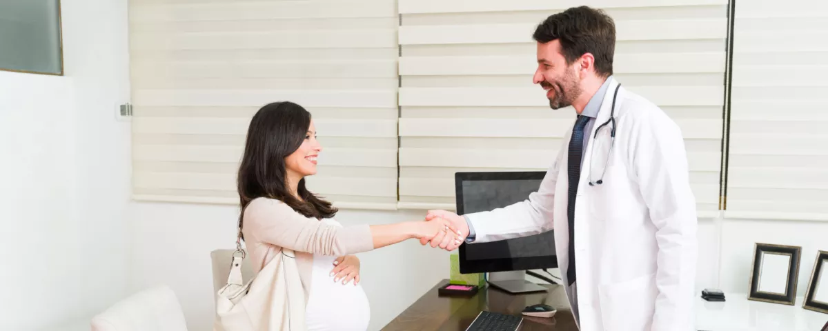 pregnant woman shaking hands with OBGYN doctor