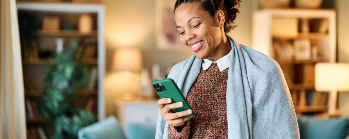 woman looking at her phone with a blanket around her shoulders