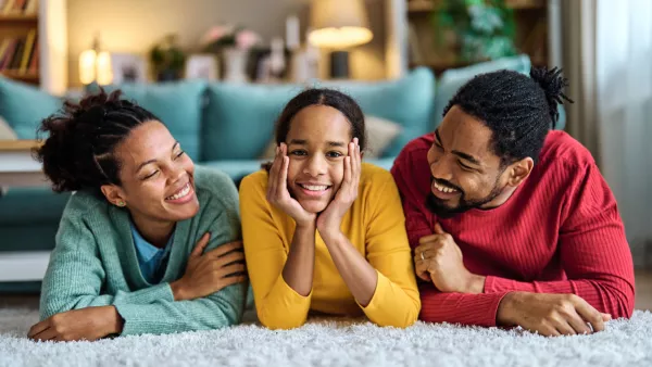 man, woman, and daughter laying on the carpet smiling