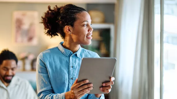 woman holding a tablet and looking out the window