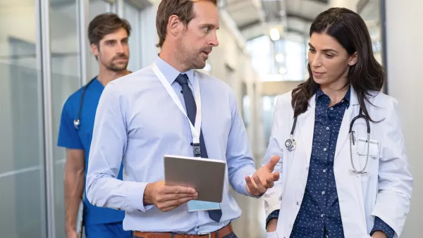 male consultant talking to female doctor in hallway holding a tablet