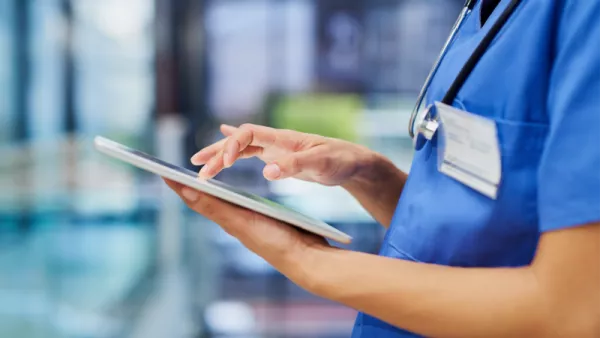 close-up of doctor in scrubs using a tablet computer