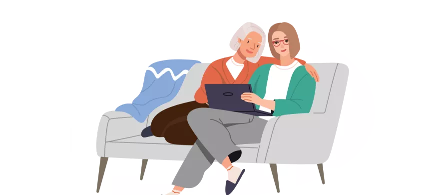 two women sitting on a couch looking at a computer