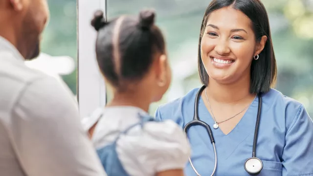 female nurse smiling at child and father