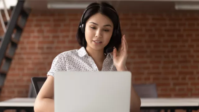 asian woman wearing headset in front of a computer