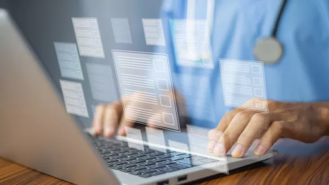 close-up image of doctor's hands typing on a keyboard with graphics of documents