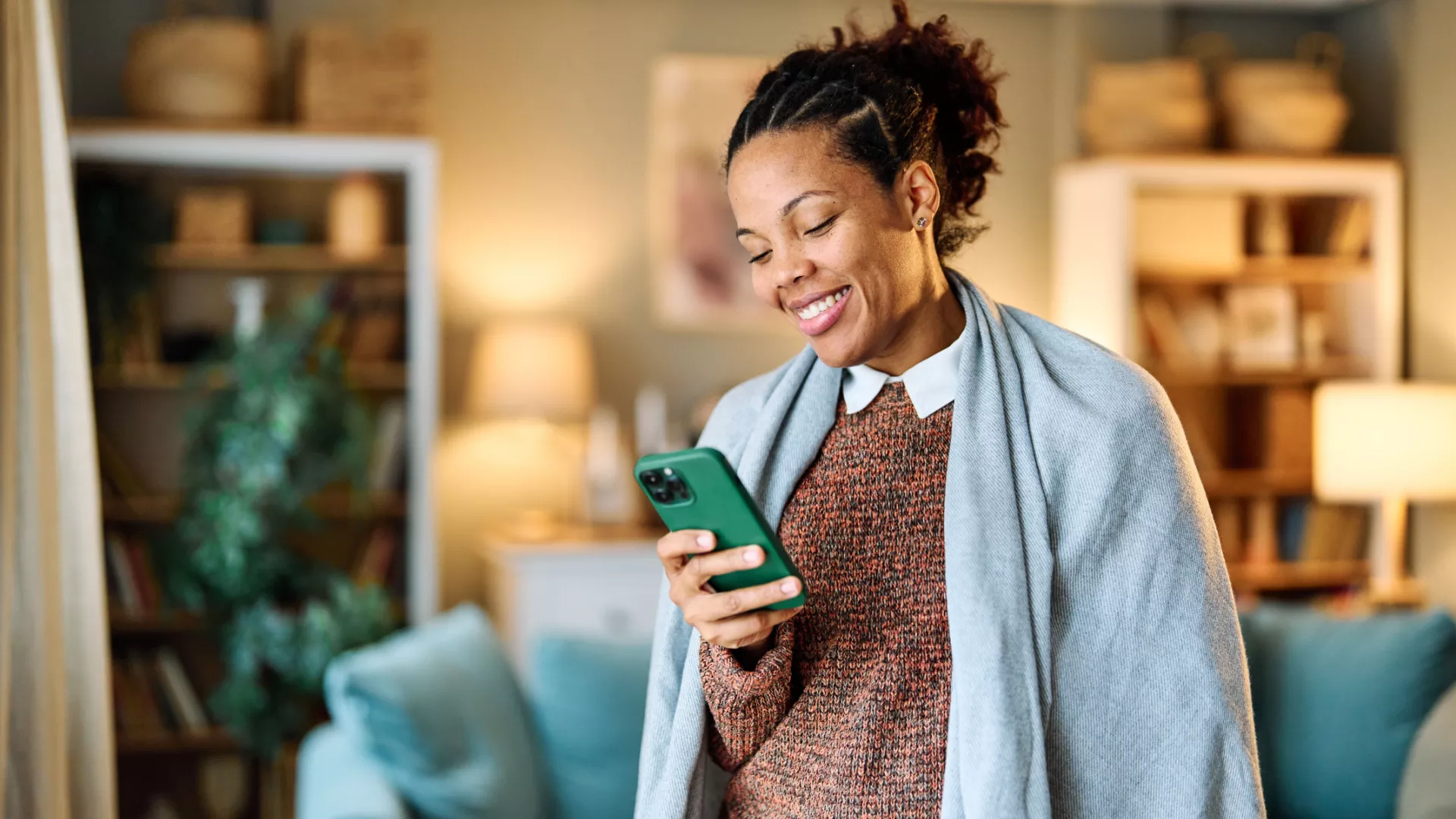 woman looking at her phone with a blanket around her shoulders