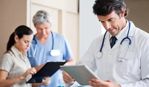 Doctor reviewing electronic health records on his tablet through a mobile app.