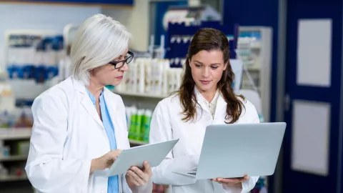 two female doctors looking at a tablet and laptop