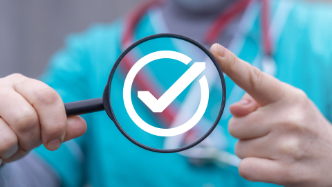 person in scrubs holding a magnifying glass with a checkmark in the middle of it