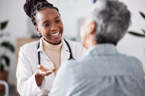 black woman doctor smiling talking to elderly patient