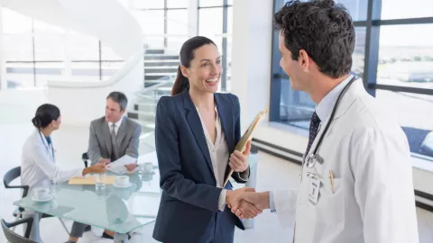 woman and doctor shaking hands in a modern office