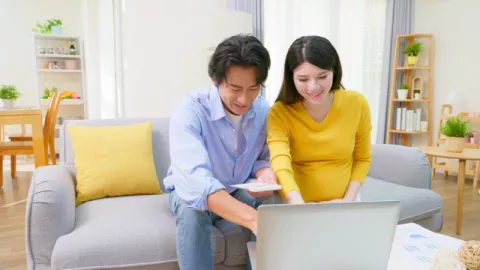 man and pregnant woman on a couch looking at a computer