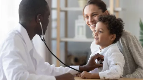 pediatrician checking heartbeat of child