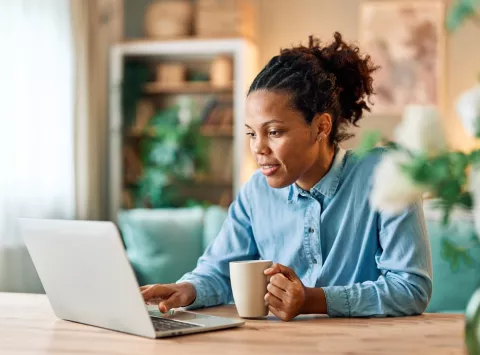 woman looking at computer with a cup of coffee